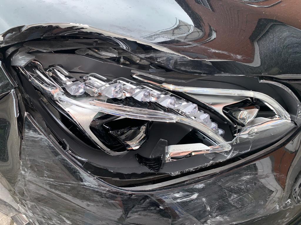 Zerbrochene Abdeckung eines Mercedes-Scheinwerfers mit beschädigten angrenzenden Karosserieteilen